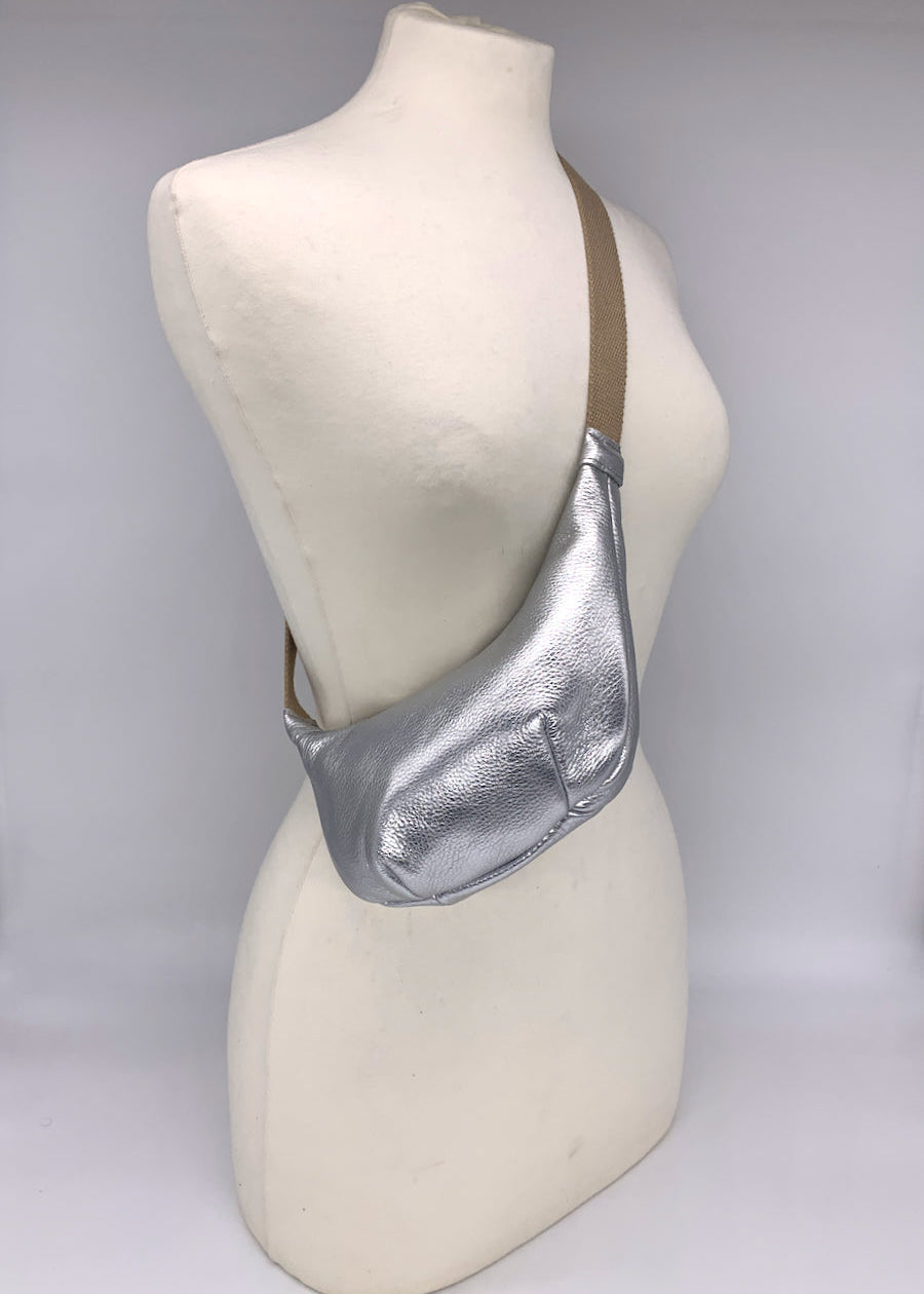 Small crossbody bag in silver leather worn across a mannequin