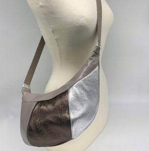 Crossbody panelled leather bag comprising ghost, antique gold and silver worn across mannequin