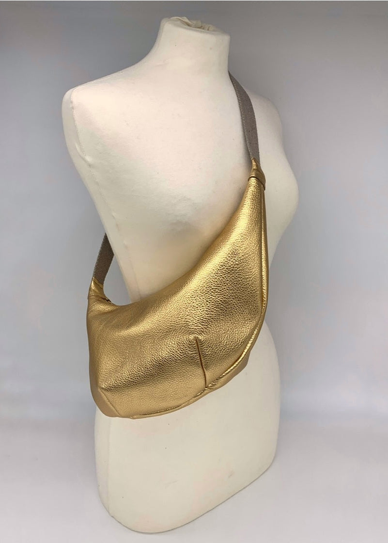 gold leather crossbody bag worn across a mannequin