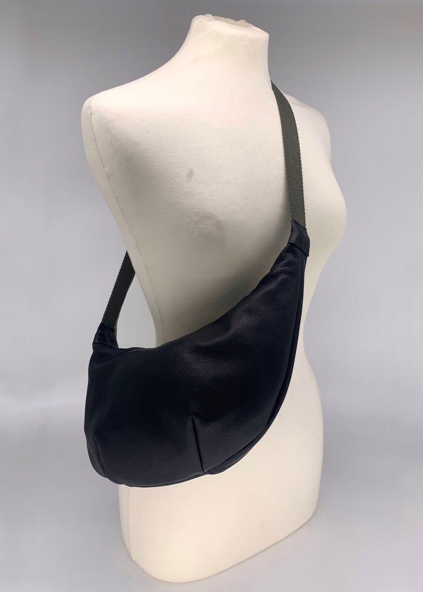 matte black leather crossbody bag worn across a mannequin
