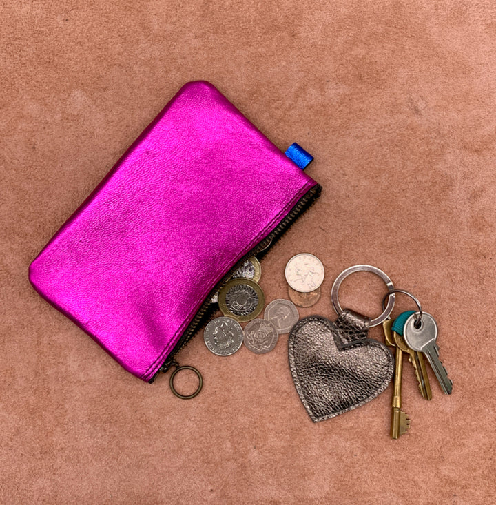 Soft leather purse in eletric pink with a heart keyring and some coins.